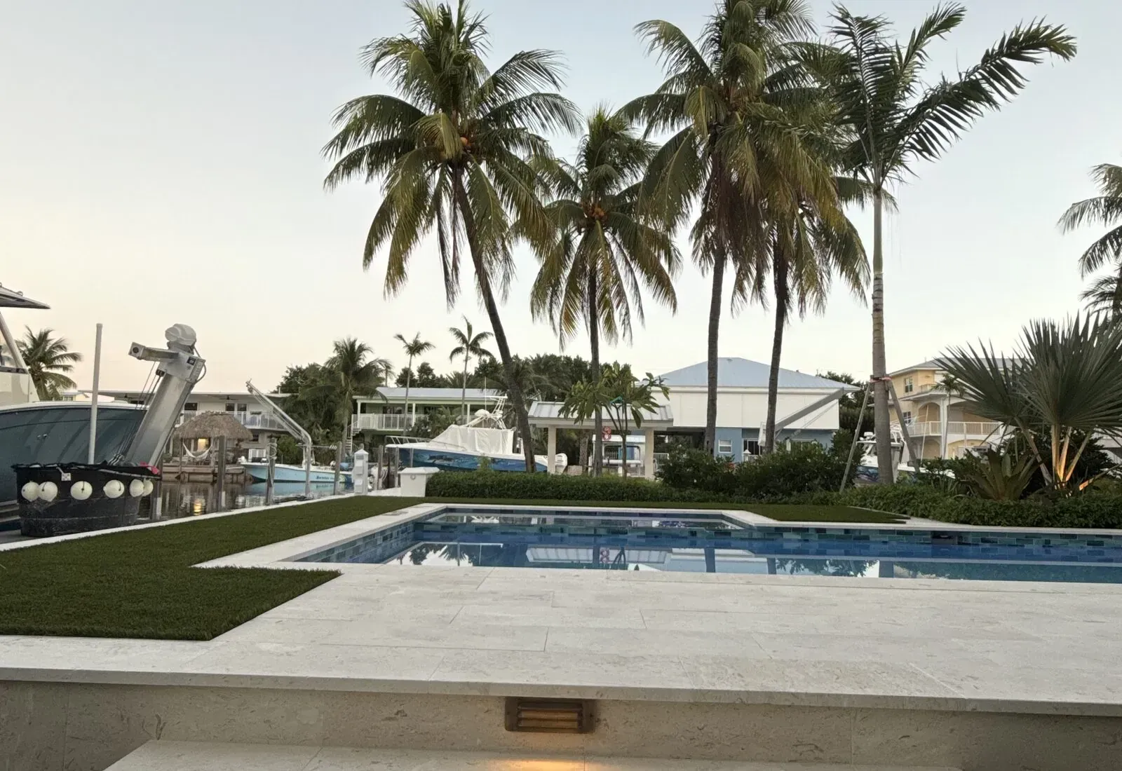 Travertine pool deck and paver hardscape with palms at dusk in the Florida Keys
